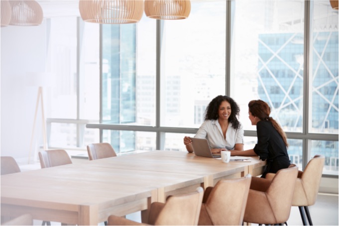 Two female Panorama employees talking in a large boardroom