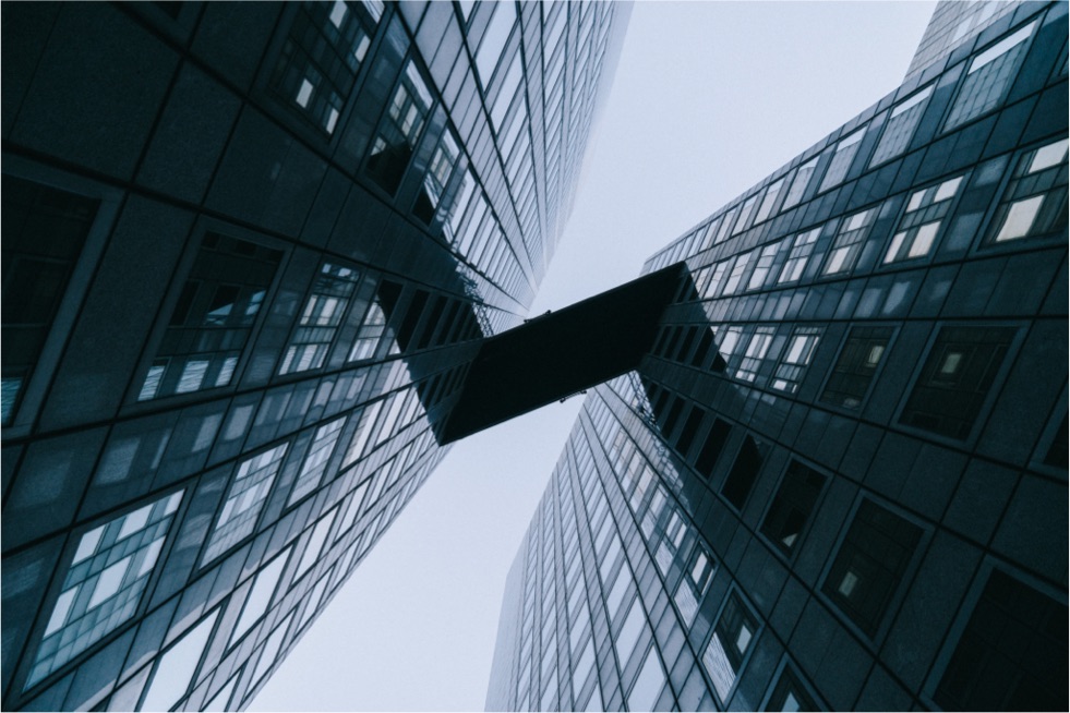 Looking up at a crosswalk between two bulidings against a gray sky