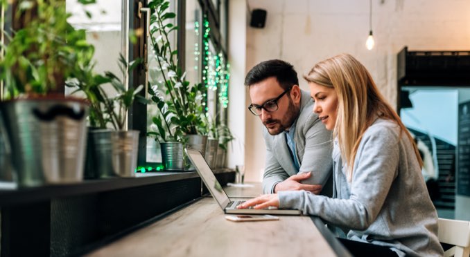 A man and woman looking at a laptop together reviewing employee benefits