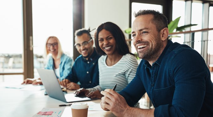 Four smiling people working at a table discussing property and casualty